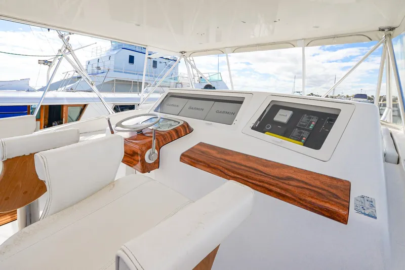 Slide: The Image of 1999 Viking 55 Convertible yacht helm with wood accents and modern navigation equipment. - 22