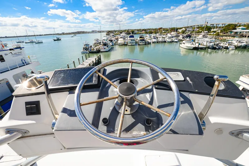Slide: The Image of Steering wheel of a 1999 Viking 55 Convertible yacht overlooking a marina. - 24