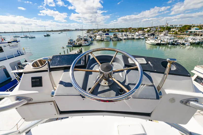 Slide: The Image of Steering wheel of a 1999 Viking 55 Convertible yacht overlooking a marina. - 27