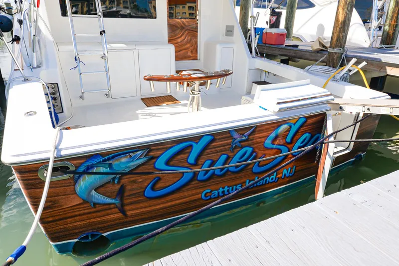 Slide: The Image of 1999 Viking 55 Convertible boat docked, featuring "Sue Sea" and fish graphic, Cattus Island, NJ. - 3