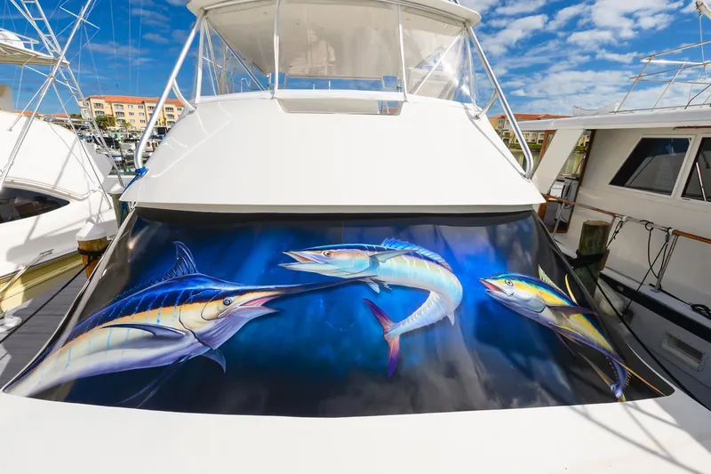 Slide: The Image of 1999 Viking 55 Convertible yacht with vibrant fish artwork on the stern, docked under a blue sky. - 31
