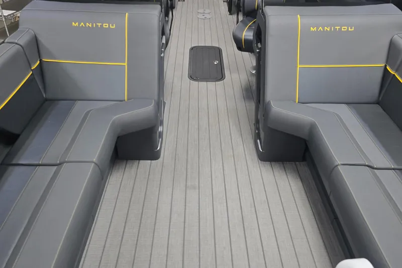Slide: The Image of 2025 Manitou Explore Navigator boat interior with gray seating and yellow accents. - 9