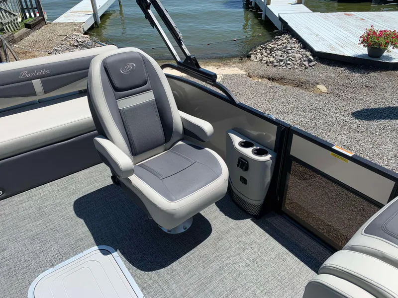Slide: The Image of 2025 Barletta Cabrio 22UC boat interior with gray seating and cup holders by the water. - 13