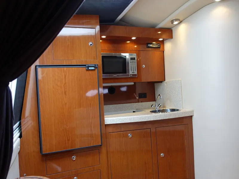 Slide: The Image of 2006 Regal 3560 Commodore yacht kitchen with wood cabinets, microwave, and sink. - 12