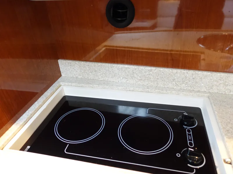 Slide: The Image of 2006 Regal 3560 Commodore yacht kitchen with electric stovetop and wooden cabinetry. - 21