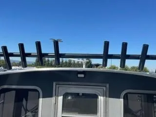 Slide: The Image of 2025 Spartan 2600 Olympia boat with rod holders against a clear blue sky. - 12