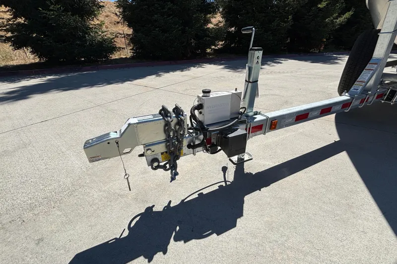 Slide: The Image of Trailer hitch of 2025 Spartan 2600 Olympia on concrete surface, surrounded by trees. - 25