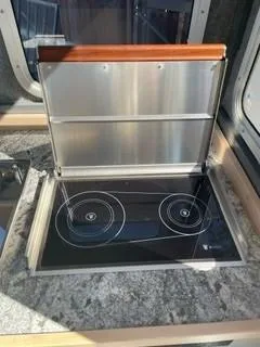 Slide: The Image of 2025 Spartan 2600 Olympia RV kitchen with modern induction cooktop and sleek countertop design. - 27