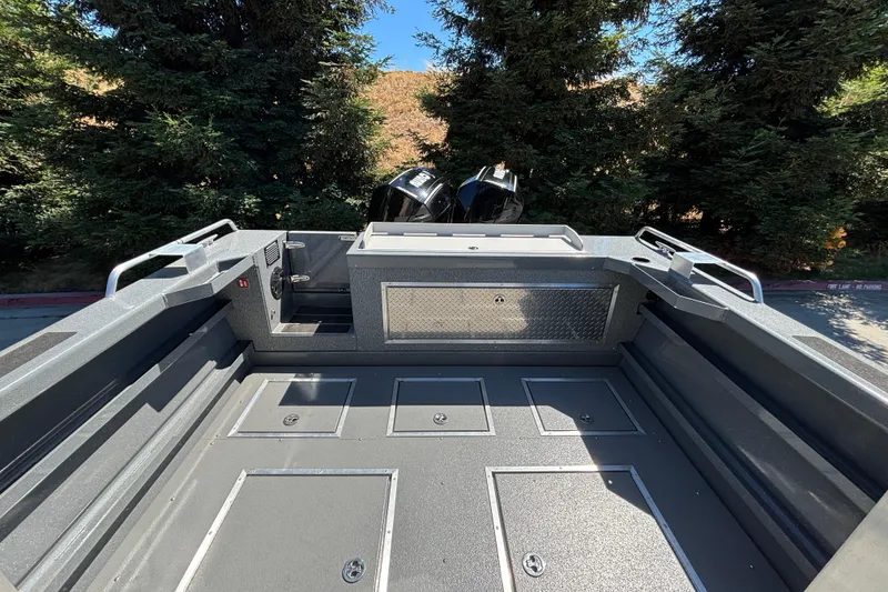 Slide: The Image of 2025 Spartan 2600 Olympia boat interior with storage compartments, set against a backdrop of trees. - 12