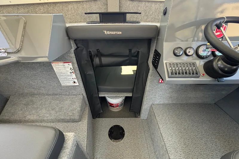 Slide: The Image of Interior of 2025 Spartan 2600 Olympia boat, featuring steering controls and storage area. - 51