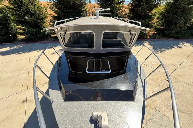 Slide: The Image of 2025 Spartan 2600 Olympia boat, front view, docked with trees in background. - 2