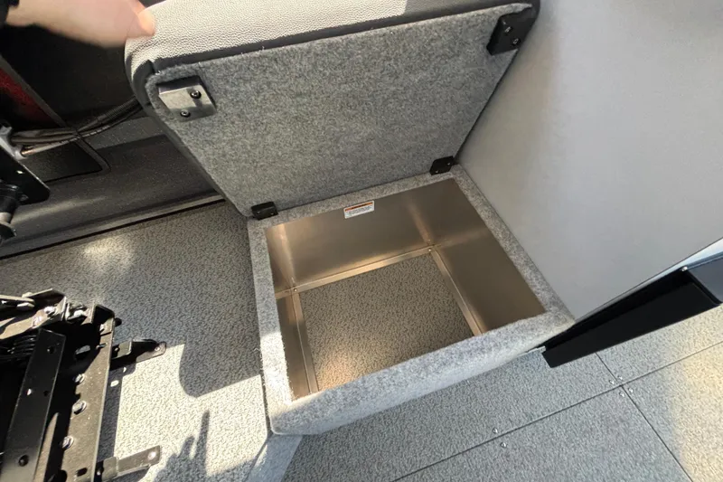 Slide: The Image of Open storage compartment in 2025 Spartan 2600 Olympia boat, featuring carpeted interior and metal lining. - 54