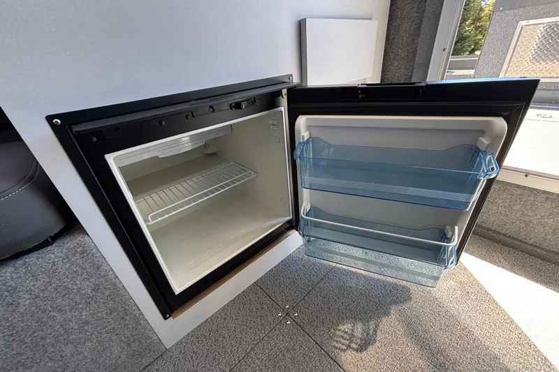 Slide: The Image of 2025 Spartan 2600 Olympia RV interior fridge with open door, showcasing storage shelves. - 60