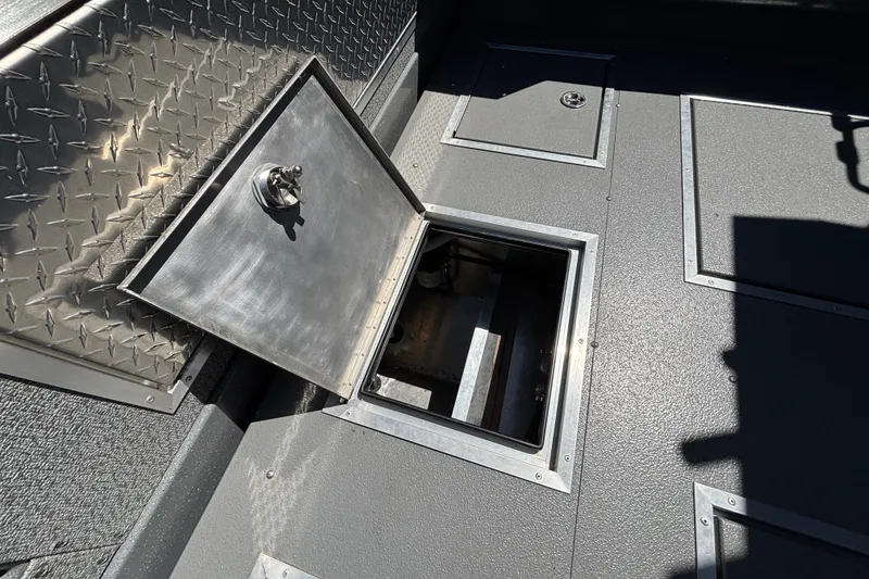 Slide: The Image of Open hatch on 2025 Spartan 2600 Olympia's textured metal floor, showcasing storage compartment. - 14