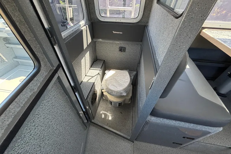 Slide: The Image of Interior of 2025 Spartan 2600 Olympia boat featuring compact toilet area. - 27