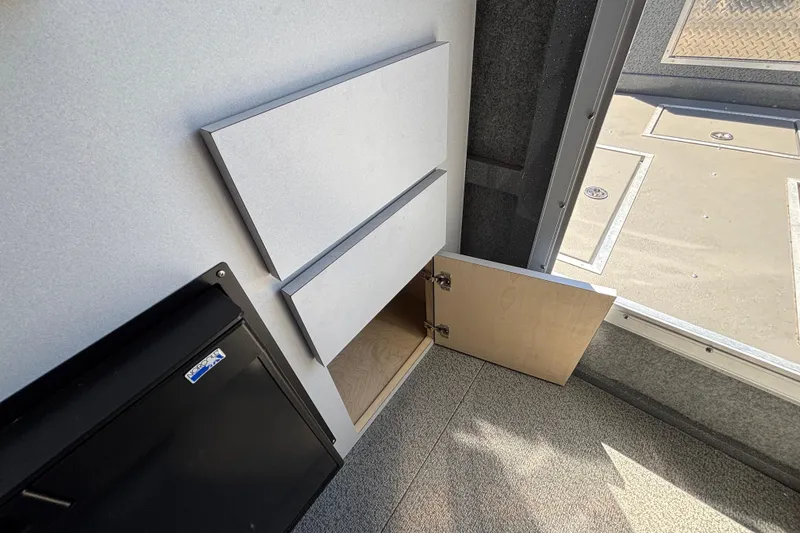 Slide: The Image of Interior storage compartment in 2025 Spartan 2600 Olympia, featuring open cabinet and carpeted flooring. - 50
