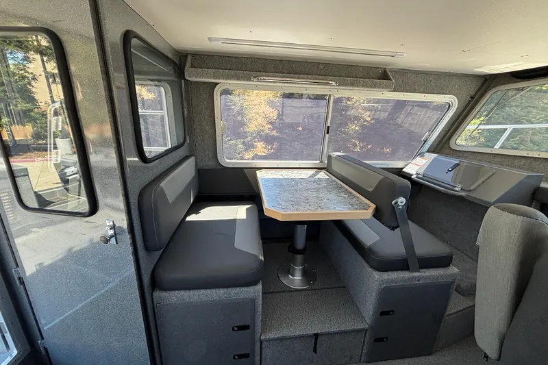 Slide: The Image of Interior of 2025 Spartan 2600 Olympia boat with seating and table, featuring large windows. - 31