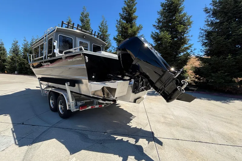 Slide: The Image of 2025 Spartan 2600 Olympia boat on trailer, parked outdoors with trees in background. - 8