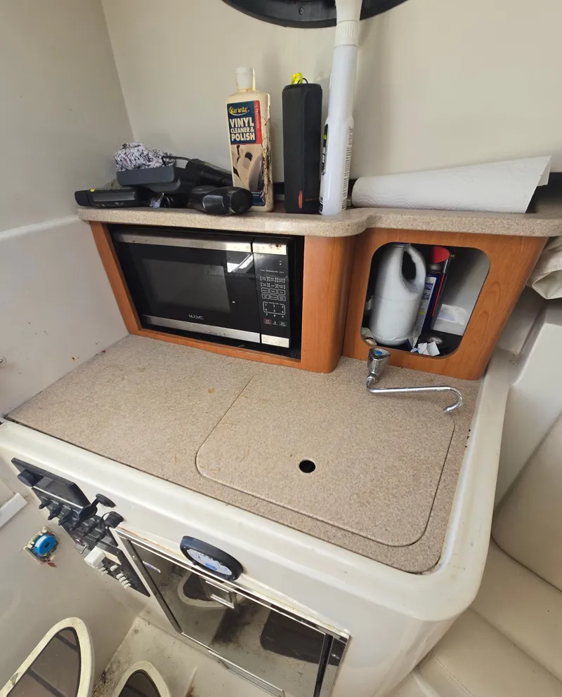 Slide: The Image of 2015 Sailfish 270 WAC boat interior with microwave, sink, and storage area. - 11
