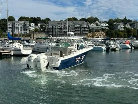Slide: The Image of 2016 Sailfish 325 DC boat in marina, surrounded by other boats and waterfront buildings. - 10