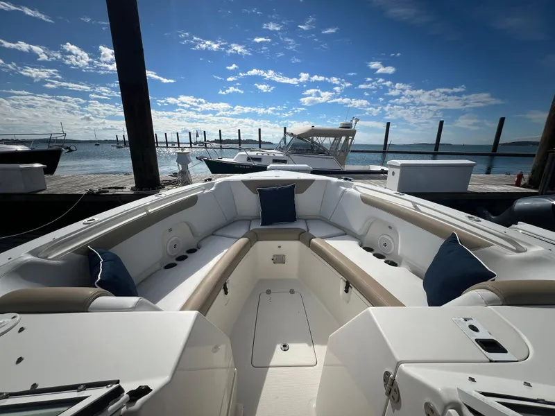 Slide: The Image of 2016 Sailfish 325 DC boat interior with cushioned seating, docked by the water under a blue sky. - 20