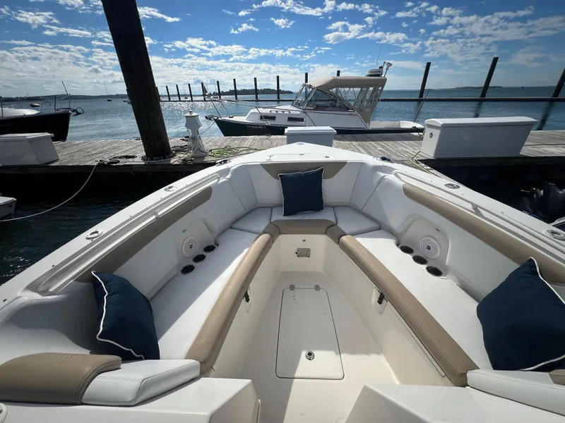 Slide: The Image of 2016 Sailfish 325 DC boat interior with cushioned seating, docked by the water. - 21