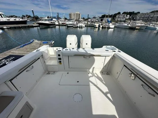 Slide: The Image of 2016 Sailfish 325 DC boat interior at marina, showcasing spacious deck and twin engines. - 22