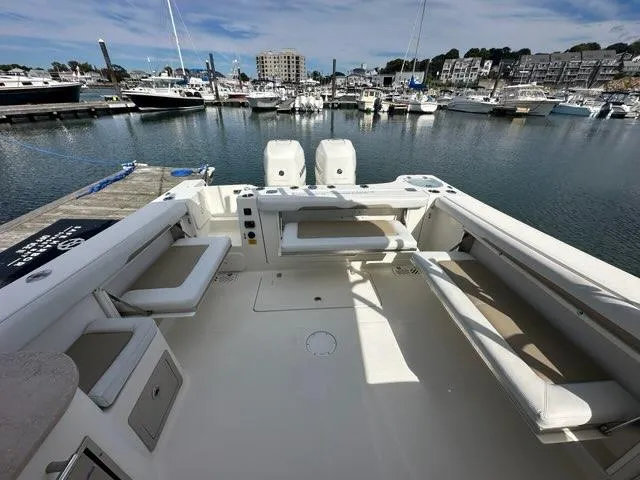 Slide: The Image of 2016 Sailfish 325 DC boat interior at marina, showcasing spacious seating and twin engines. - 23