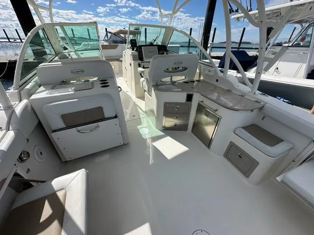 Slide: The Image of 2016 Sailfish 325 DC boat interior with seating, storage, and helm, docked under a sunny sky. - 24