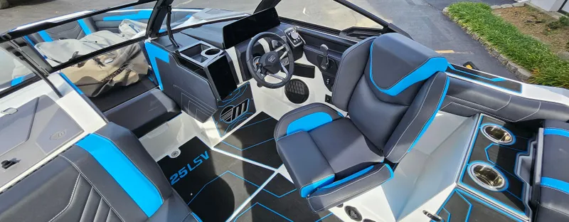 Slide: The Image of 2025 Malibu 25LSV boat interior with modern black and blue seating and dashboard. - 12