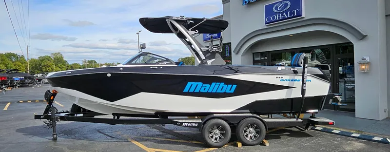 Slide: The Image of 2025 Malibu 25LSV boat on trailer outside dealership. - 3