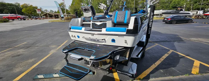 Slide: The Image of 2025 Malibu 25LSV boat with sleek design and blue accents in a parking lot. - 5