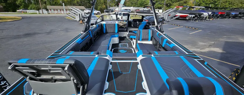 Slide: The Image of 2025 Malibu 25LSV boat interior with blue and gray seating, parked in a marina. - 7