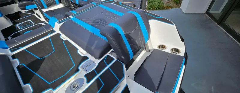 Slide: The Image of 2025 Malibu 25LSV boat interior with blue and black seating and cup holders. - 8