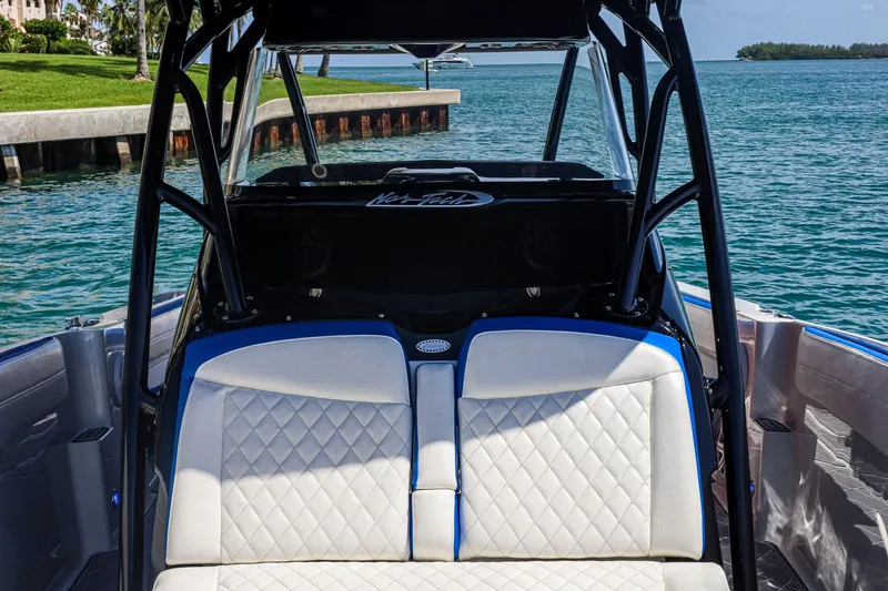 Slide: The Image of 2020 Nor-Tech 340 boat interior with white quilted seats and blue accents, near water. - 6