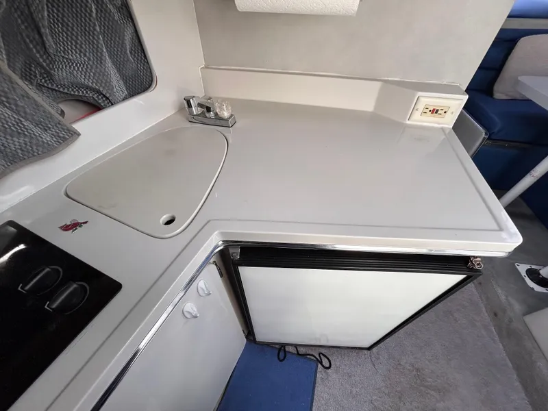 Slide: The Image of 1992 Chaparral Signature 30 boat kitchen with sink, stove, and mini-fridge. - 47