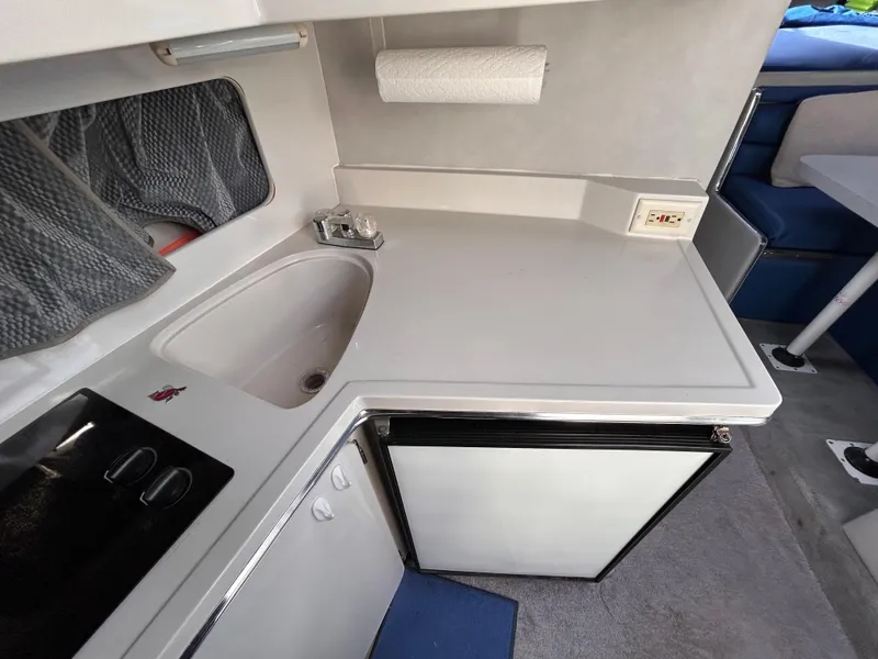 Slide: The Image of 1992 Chaparral Signature 30 boat interior kitchen with sink, stove, and mini-fridge. - 48