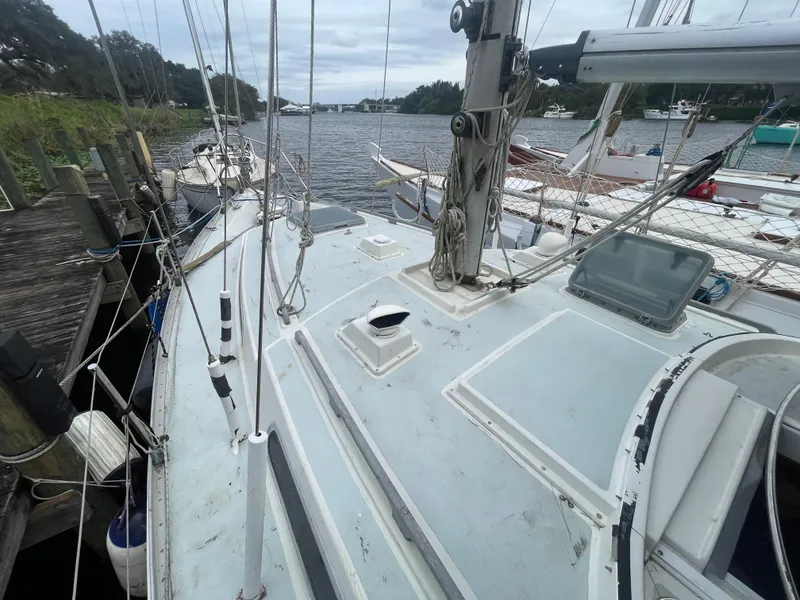 Slide: The Image of 1979 Moody 36 Classic sailboat docked by a river, showcasing deck and rigging. - 10