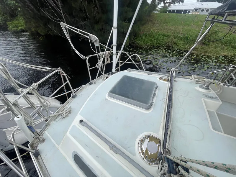 Slide: The Image of 1979 Moody 36 Classic sailboat deck near water, featuring ropes and hatch. - 20