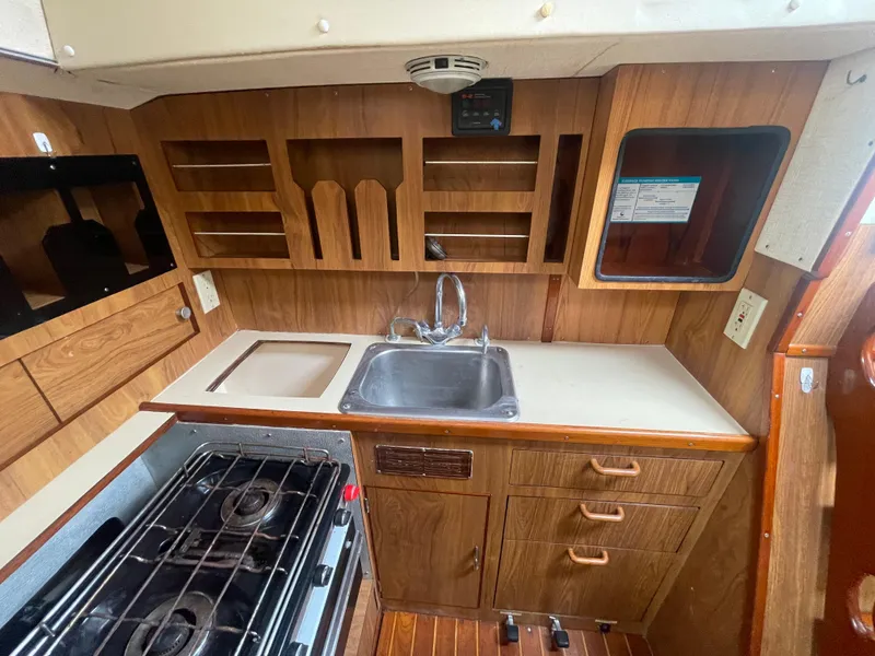 Slide: The Image of 1979 Moody 36 Classic yacht kitchen with wood cabinetry, sink, stove, and storage shelves. - 41