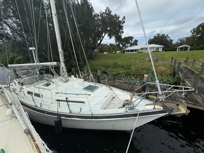 Slide: The Image of 1979 Moody 36 Classic sailboat docked by a grassy shoreline. - 7