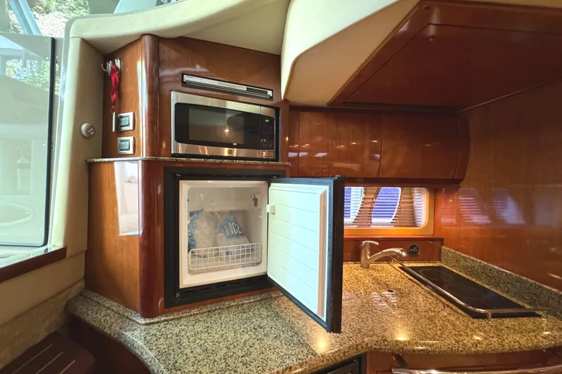 Slide: The Image of 2006 Sea Ray 38 Sundancer yacht kitchen with microwave, open fridge, and granite countertop. - 26
