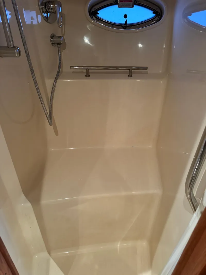 Slide: The Image of 2006 Sea Ray 38 Sundancer shower interior with chrome fixtures and porthole window. - 46