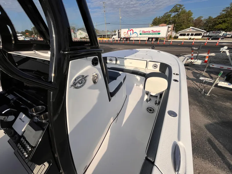 Slide: The Image of 2025 Tidewater 2700 Carolina Bay boat interior with console and seating, parked outdoors. - 10