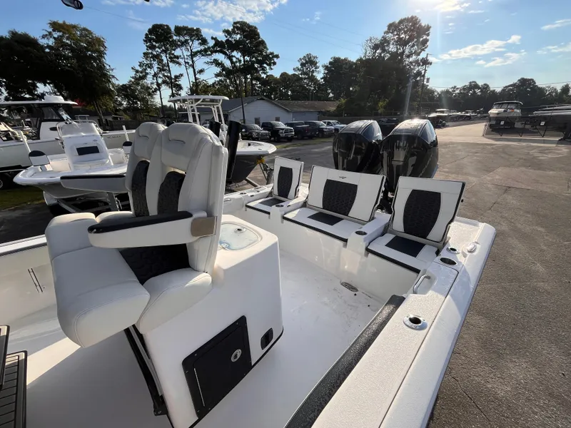 Slide: The Image of 2025 Tidewater 2700 Carolina Bay boat with dual engines and cushioned seating, parked outdoors. - 15
