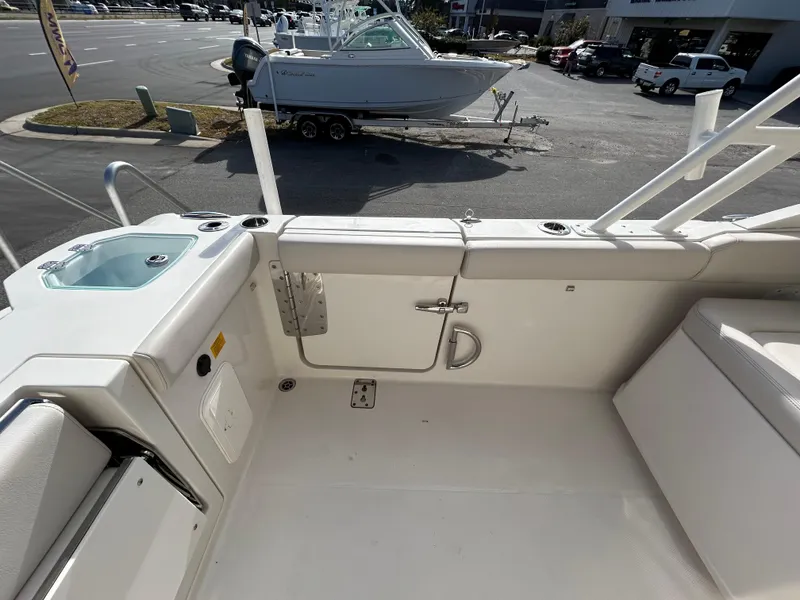 Slide: The Image of 2024 Sailfish 276 DC boat interior with seating and storage, parked outdoors. - 17