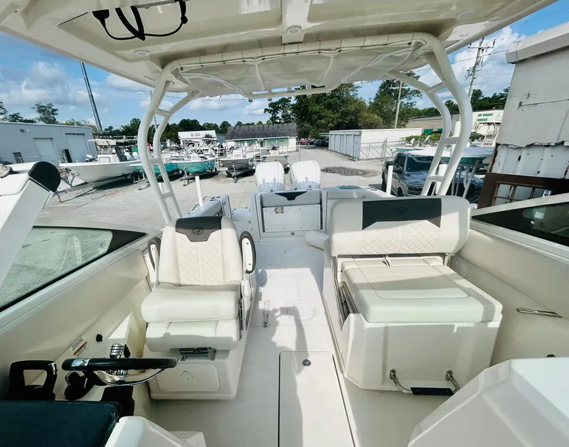 Slide: The Image of 2024 Sailfish 276 DC boat interior with seating and helm, docked at marina. - 9