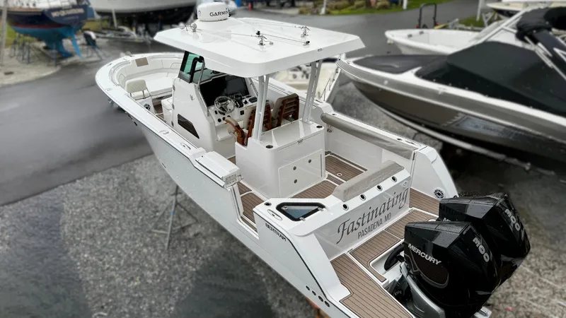 Slide: The Image of 2022 Bertram 28 CC boat with twin Mercury engines, docked in a marina. - 1