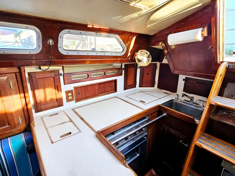 Slide: The Image of Interior of 1989 Ericson 35 MKIII sailboat with wooden cabinetry and compact kitchen area. - 36