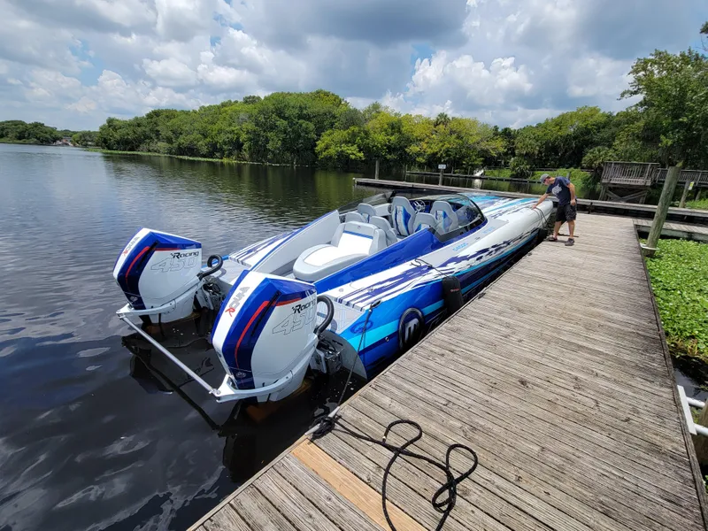 Slide: The Image of 2022 Mystic Powerboats C4000 docked on a serene lake under a cloudy sky. - 13